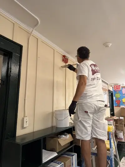 Painter brushing a fresh coat onto a wall beside a doorway