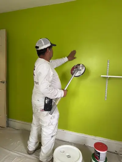 Walker Painting crew member rolling a bold green color onto a wall